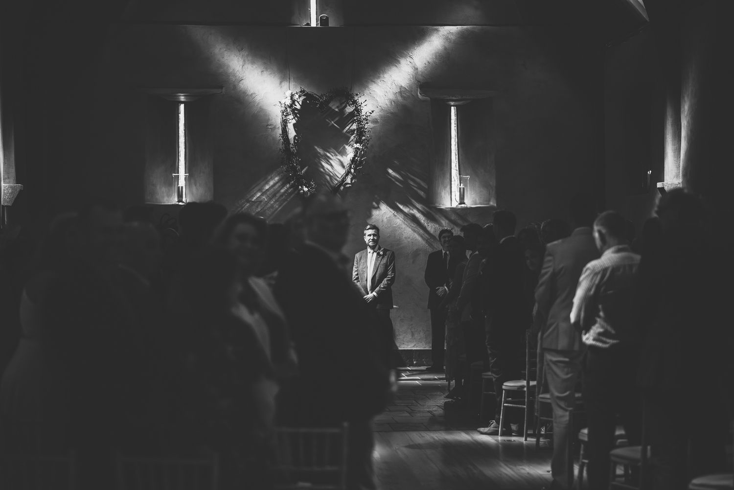 A moody black and white concert scene showing musicians performing on stage with dramatic lighting and silhouettes.