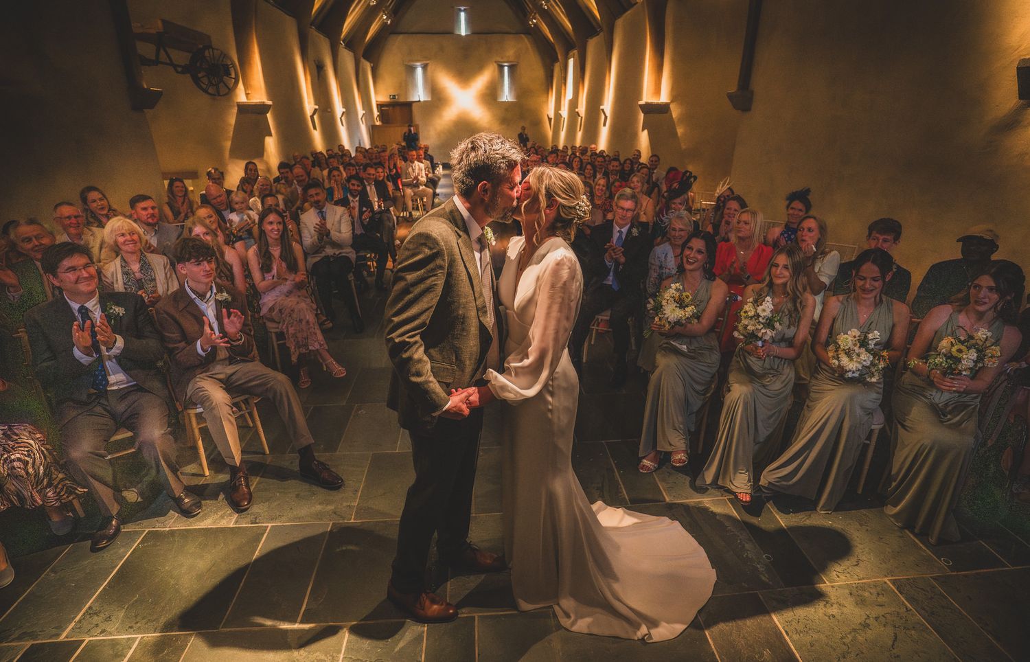 Couple dancing during their first dance at a wedding reception while guests watch from their seats in a dimly lit venue.