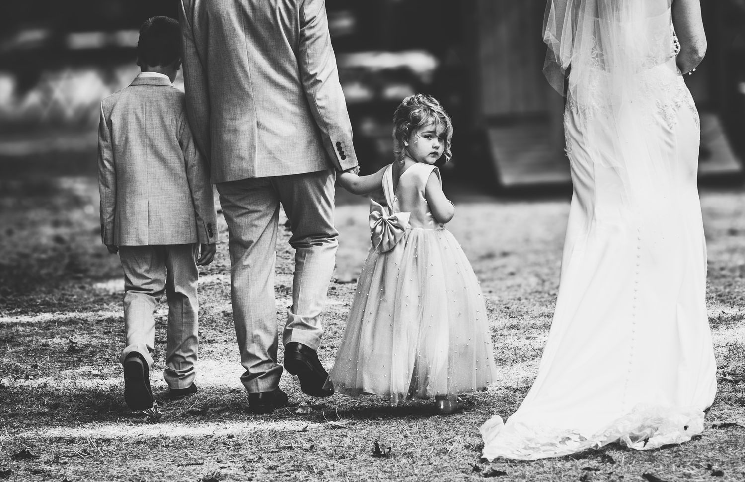 Black and white photo showing the bottom half of wedding attendees walking outdoors.