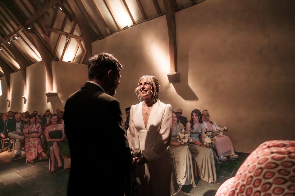 A couple shares a romantic dance on their wedding day while guests watch from the dance floor in warm lighting.