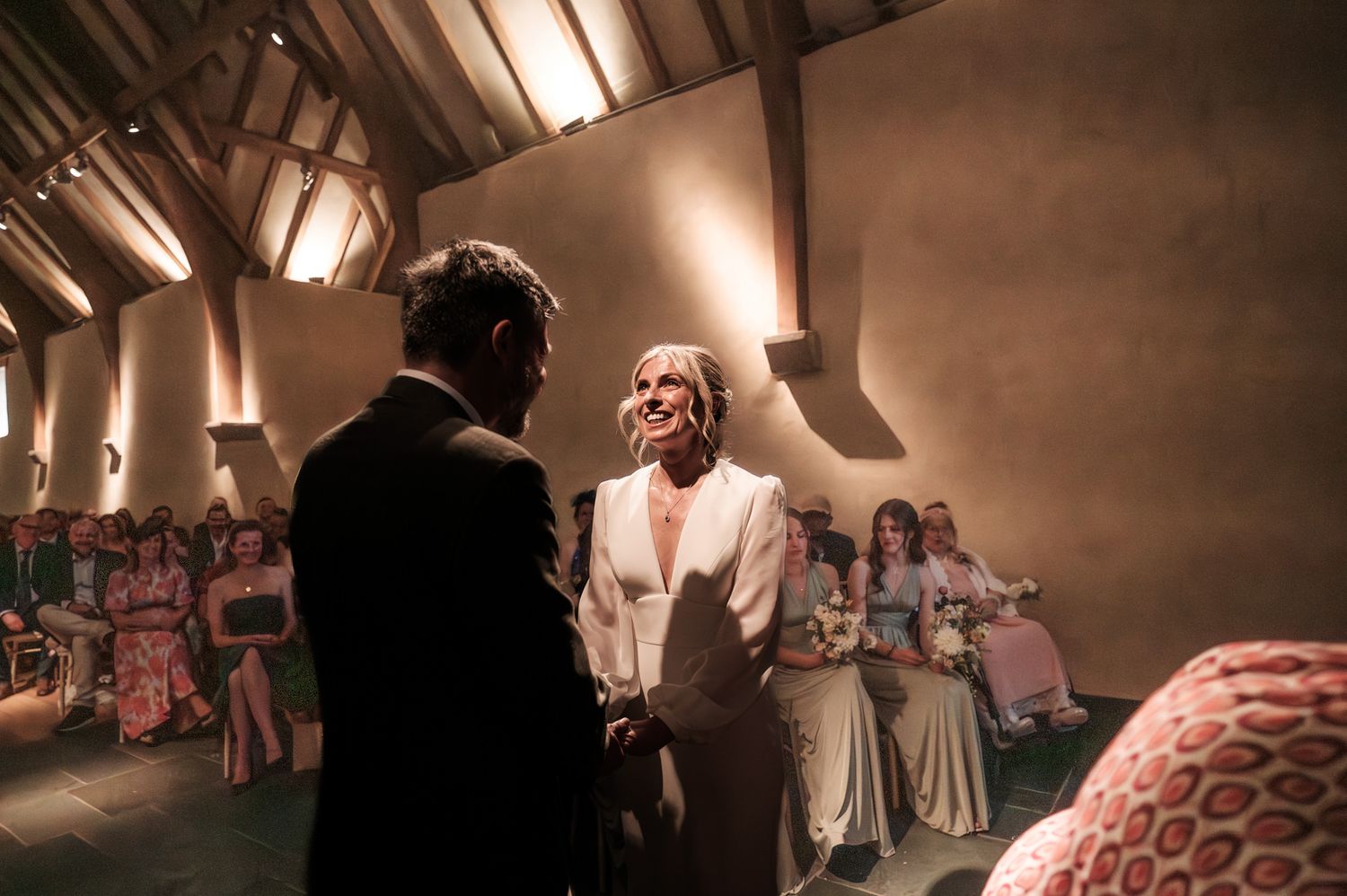 A couple shares a romantic dance on their wedding day while guests watch from the dance floor in warm lighting.