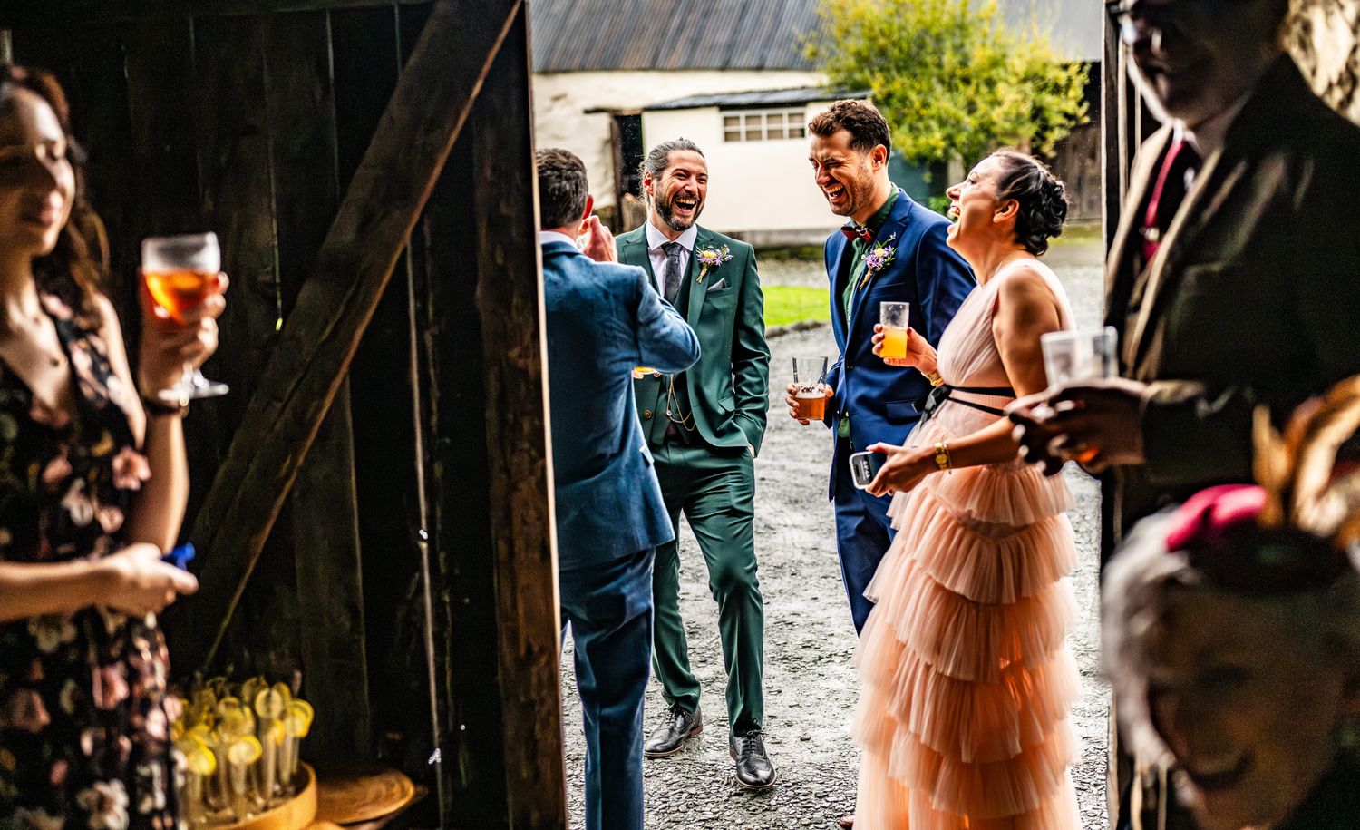 A rustic barn wedding ceremony with guests seated on wooden benches and sunlight streaming through the wooden slats.