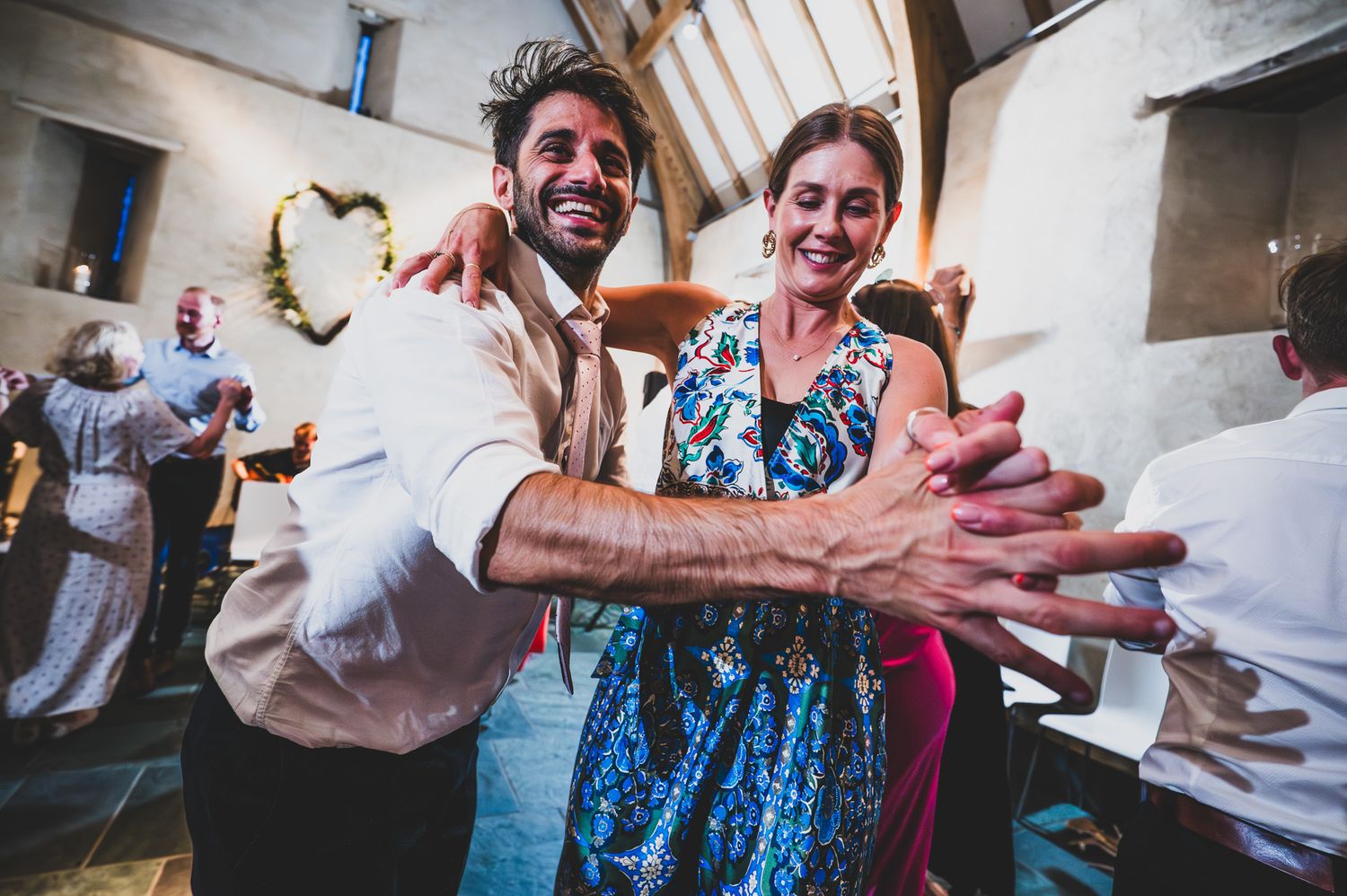 People dancing and celebrating at a lively wedding reception with joyful expressions and energetic movements.