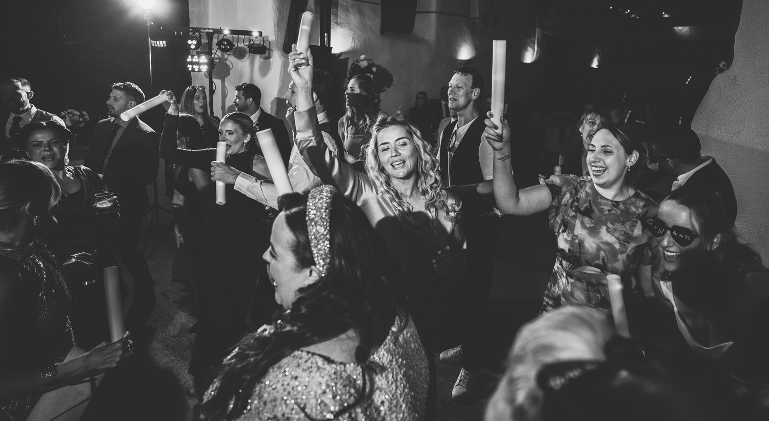 Guests dance and celebrate on a dimly lit dance floor during an evening wedding reception.