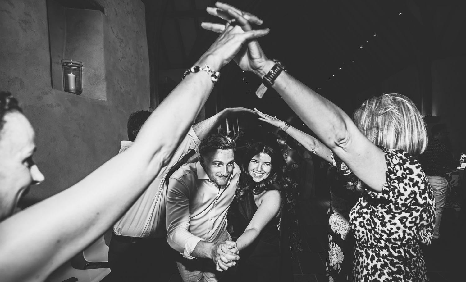 People dancing and having fun at a lively wedding reception party in black and white.