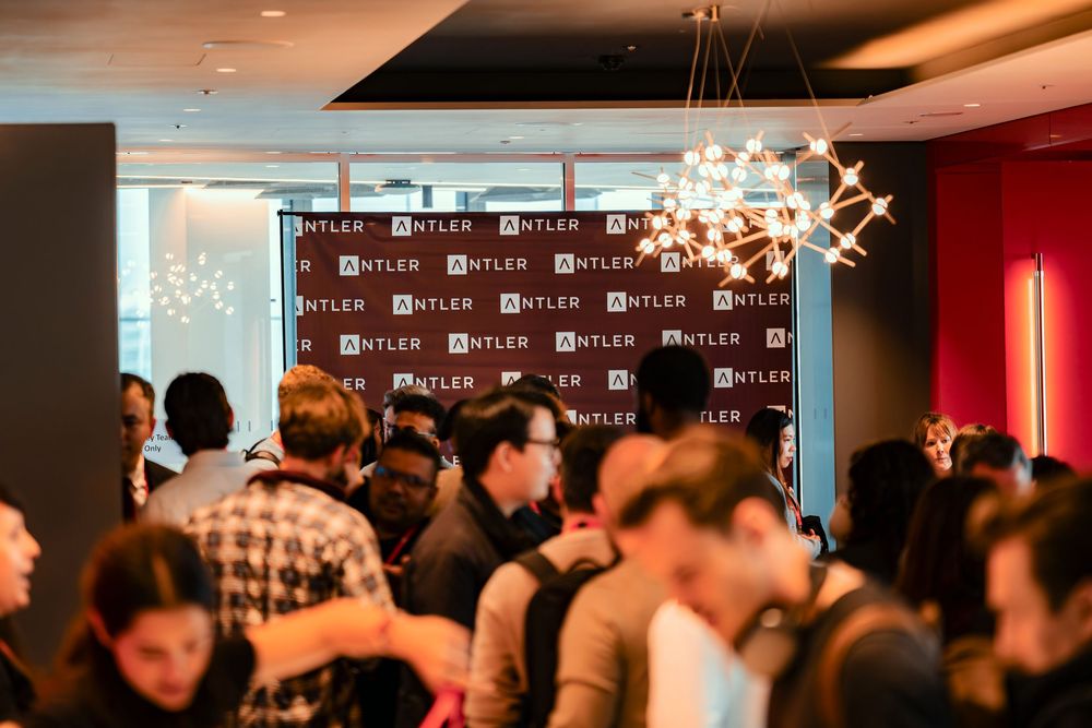 A dimly lit event space with guests mingling and socializing at an indoor gathering.