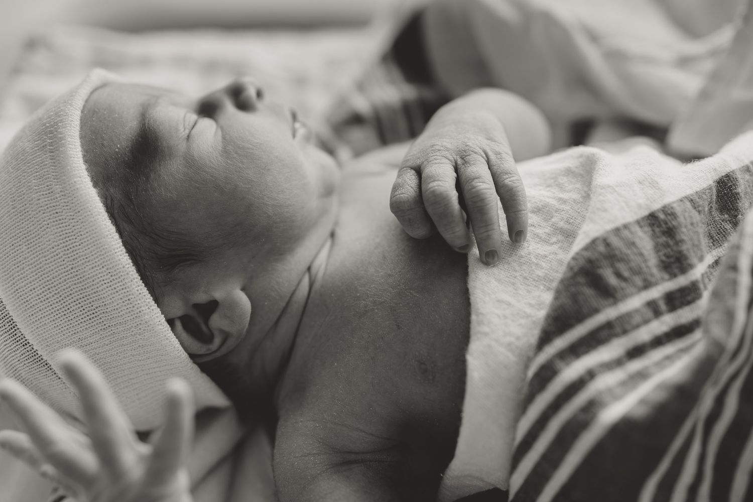Newborn baby sleeping peacefully in soft white blanket with orange accents.