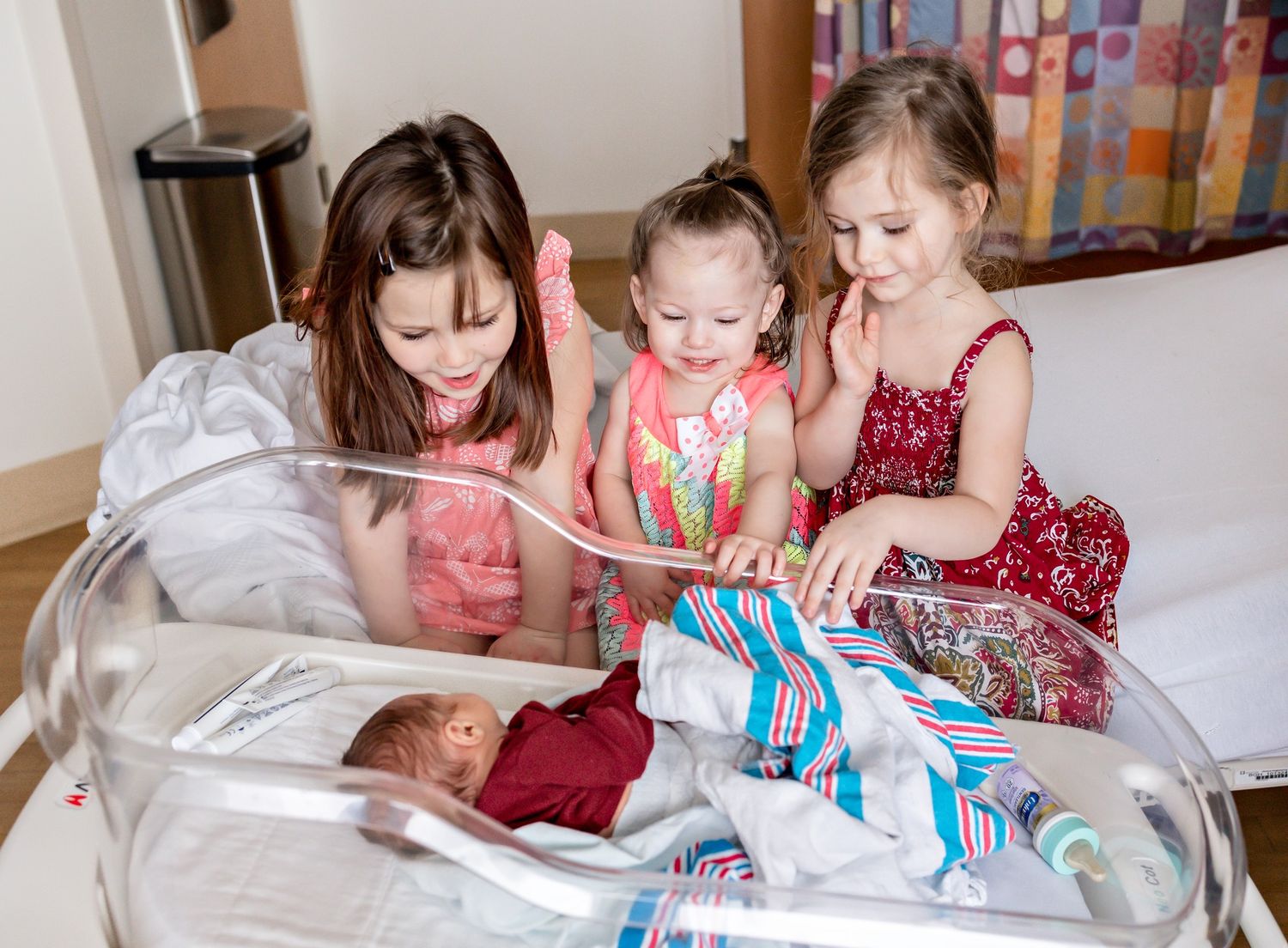 Family members gathered on bed looking at and interacting with newborn baby.