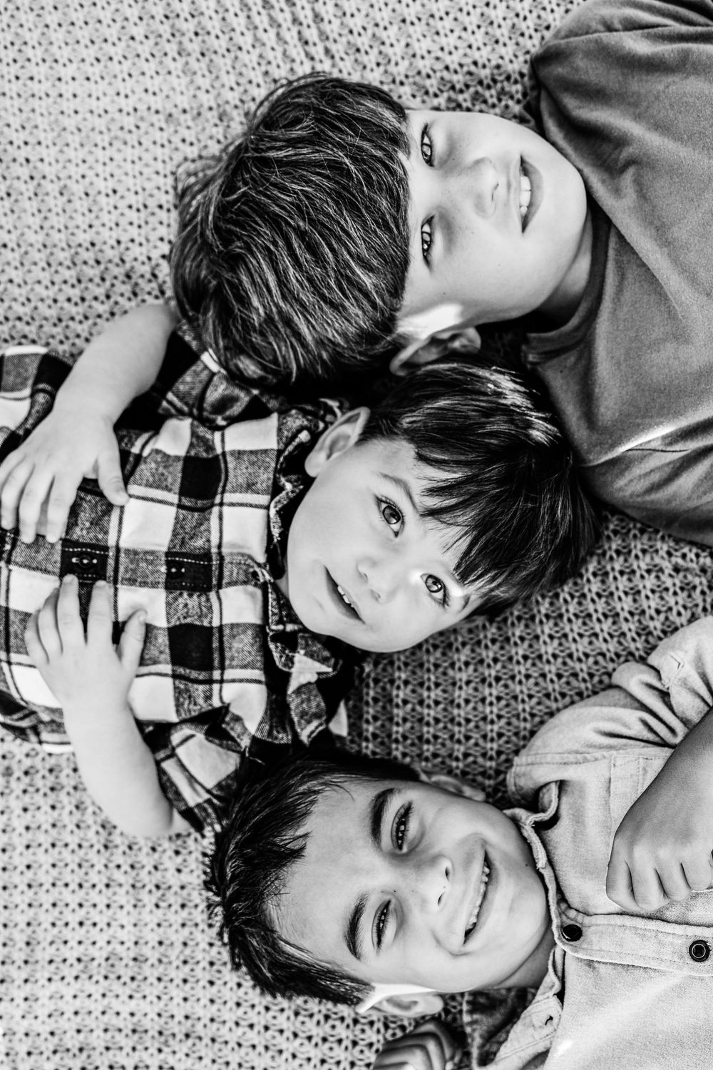 Black and white photo showing three young boys lying down on a blanket in a field in Fort Worth
