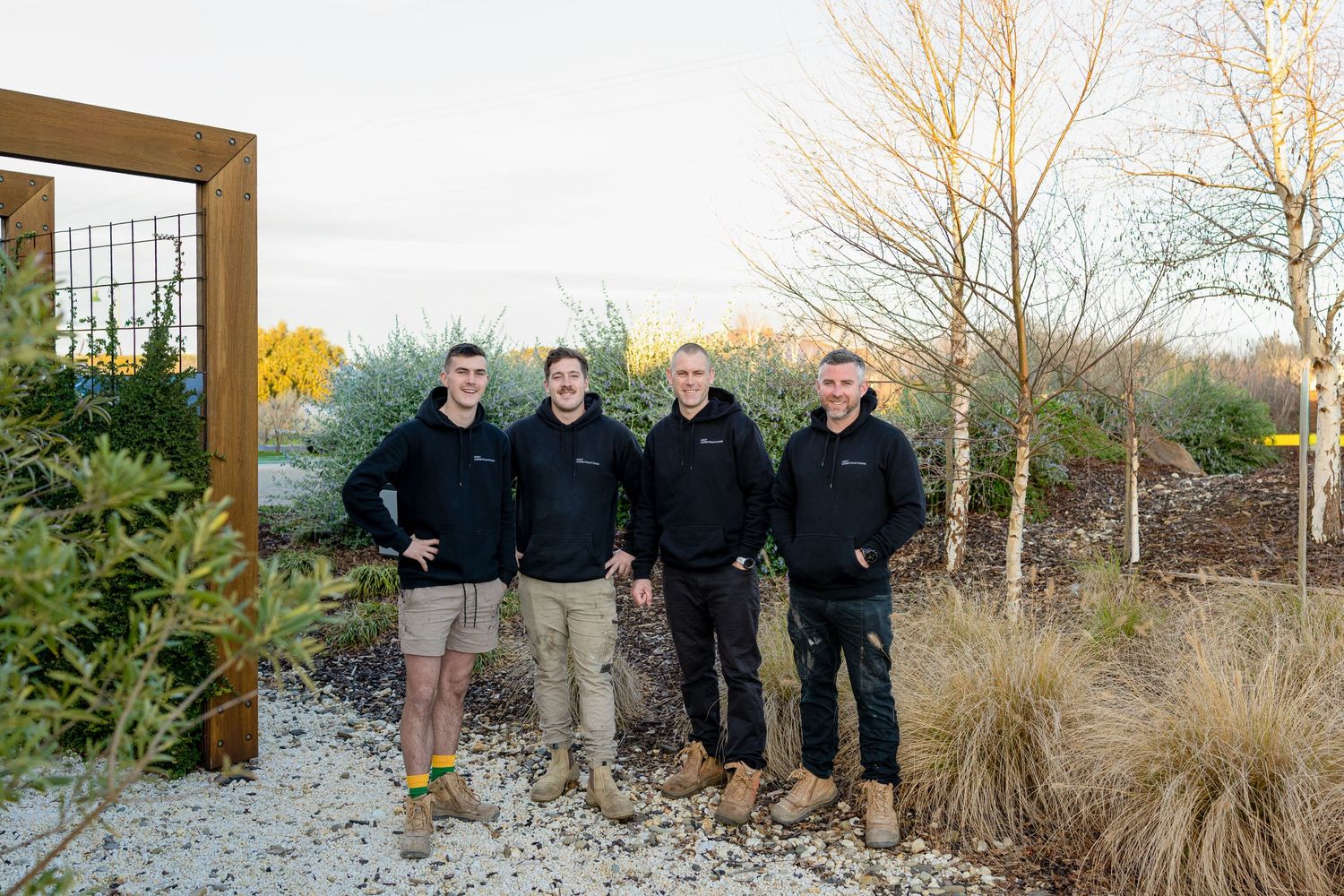 A series of five photos showing people in navy uniforms walking up wooden steps between large landscaping rocks.