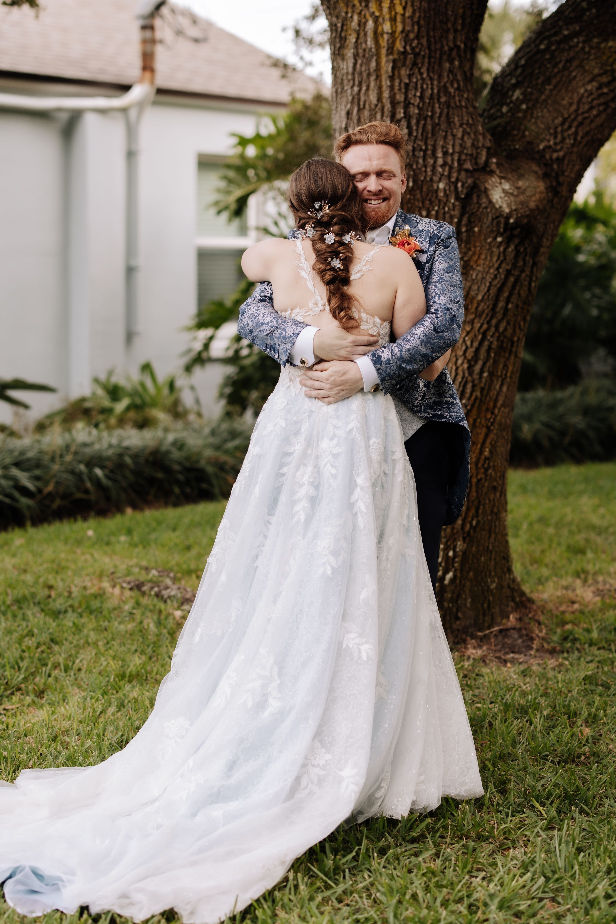 A romantic wedding couple dances and embraces on a grassy lawn near trees in a series of candid photos.