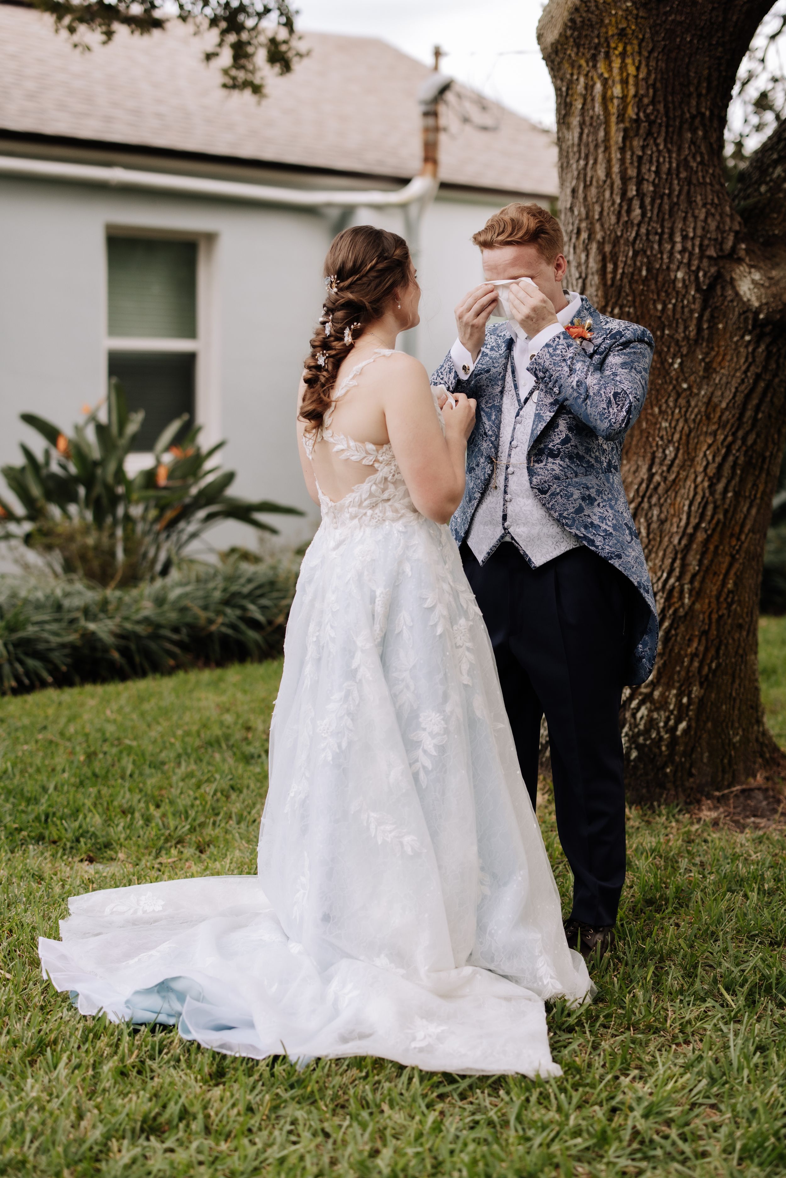 A couple shares an intimate moment in a garden setting with a white wedding gown and formal suit.