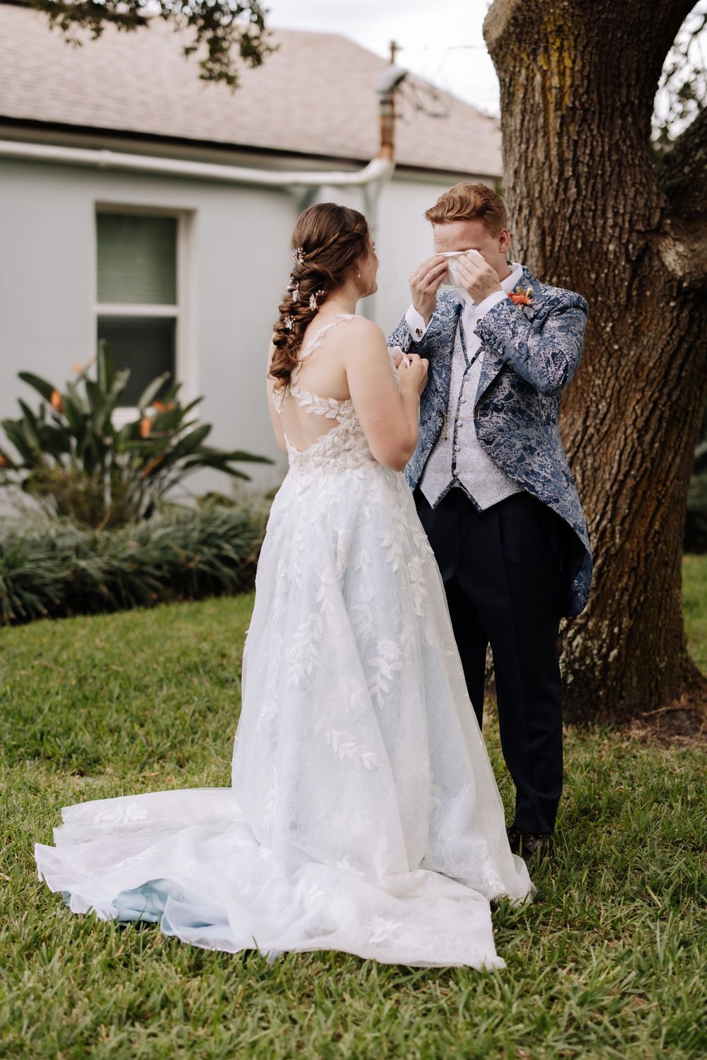 A couple shares an intimate moment in a garden setting with a white wedding gown and formal suit.