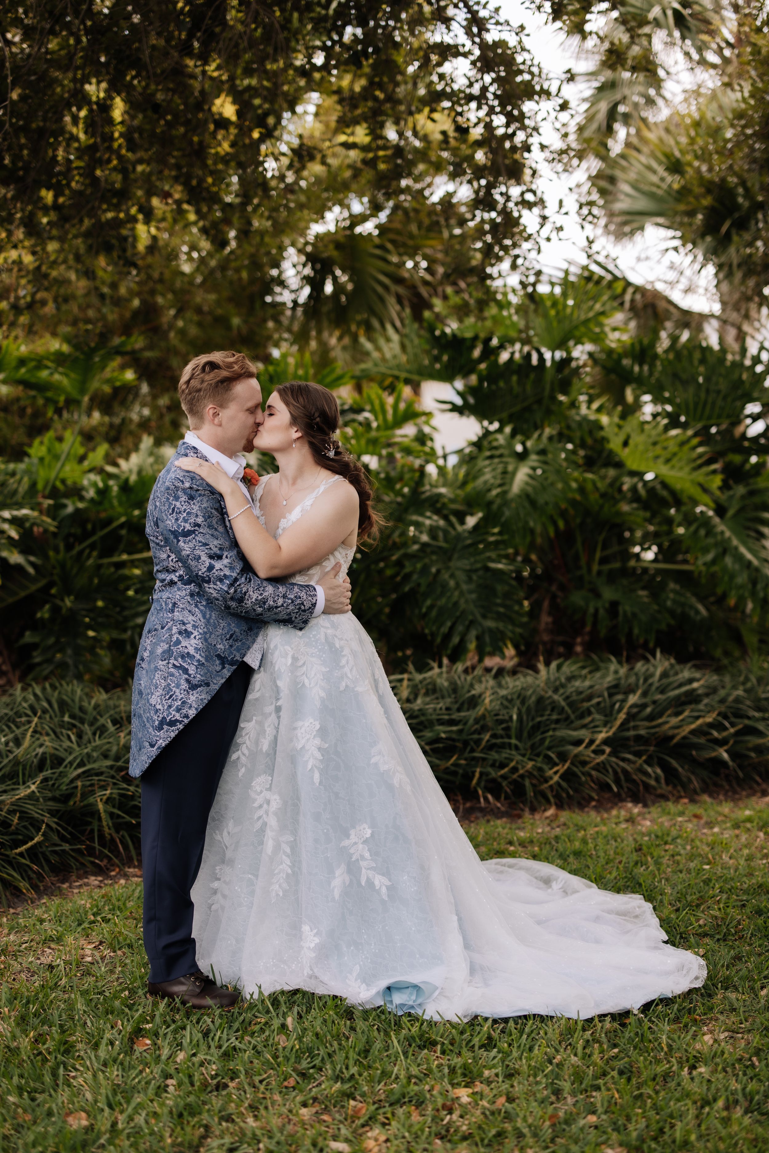 A romantic wedding couple shares intimate moments in a lush garden setting with natural greenery.