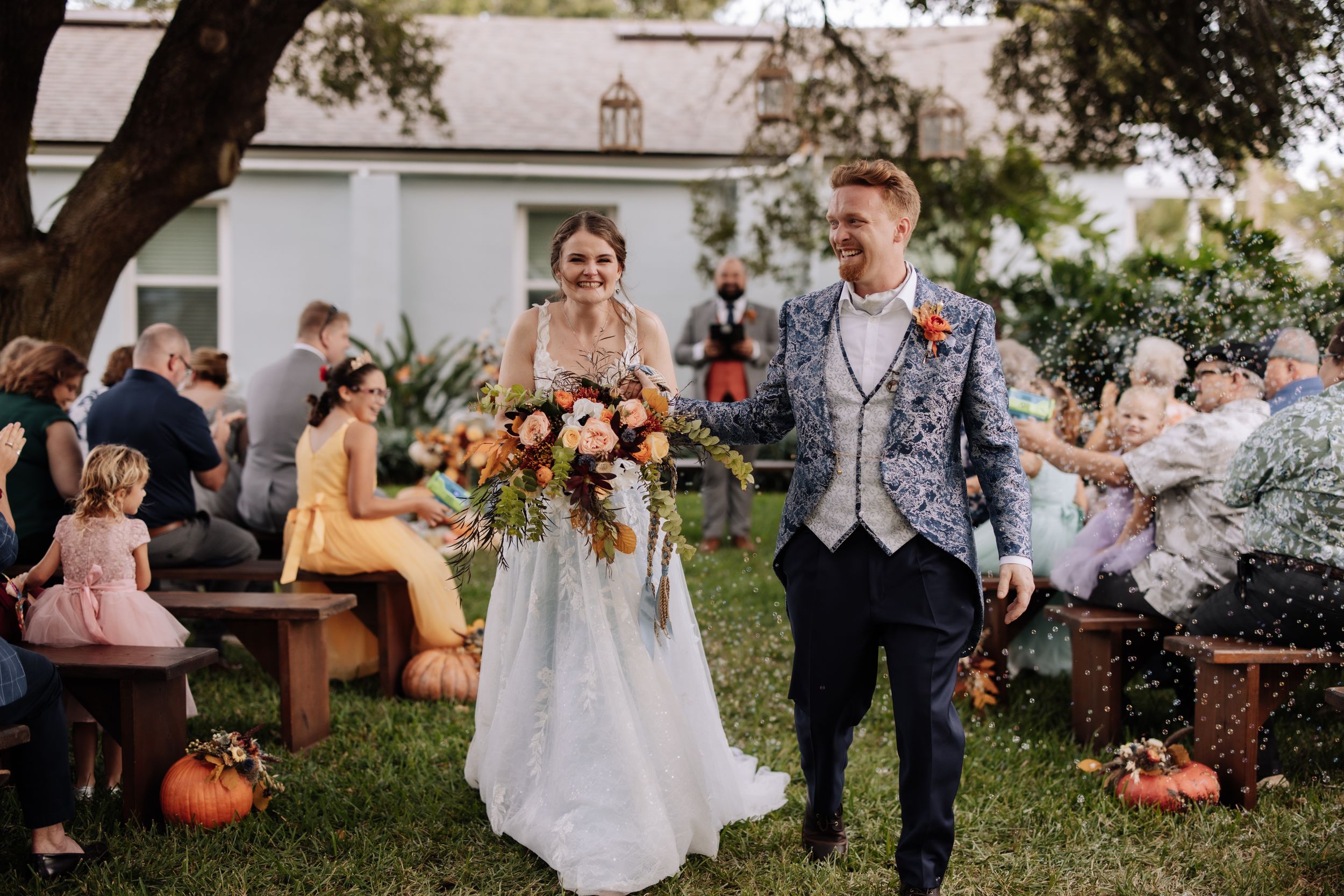 Wedding party gathers outdoors in autumn setting with pumpkin decorations and rustic charm.