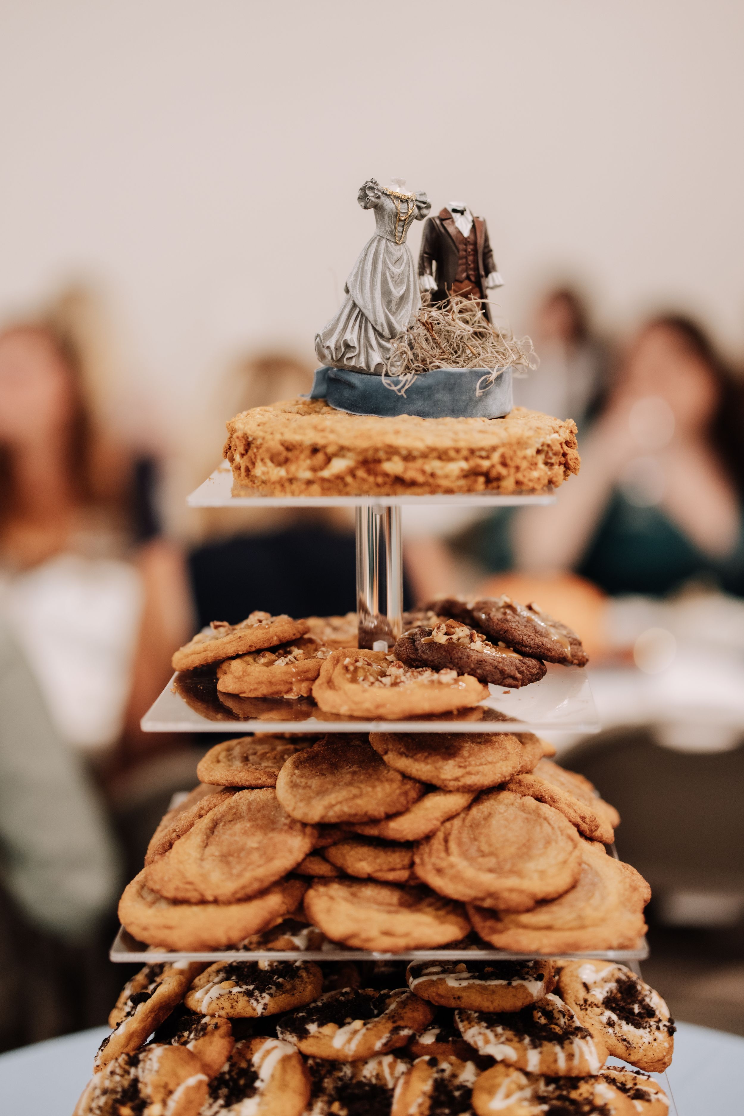 Stacked chocolate chip cookies on tiered serving platters at a wedding dessert table display.