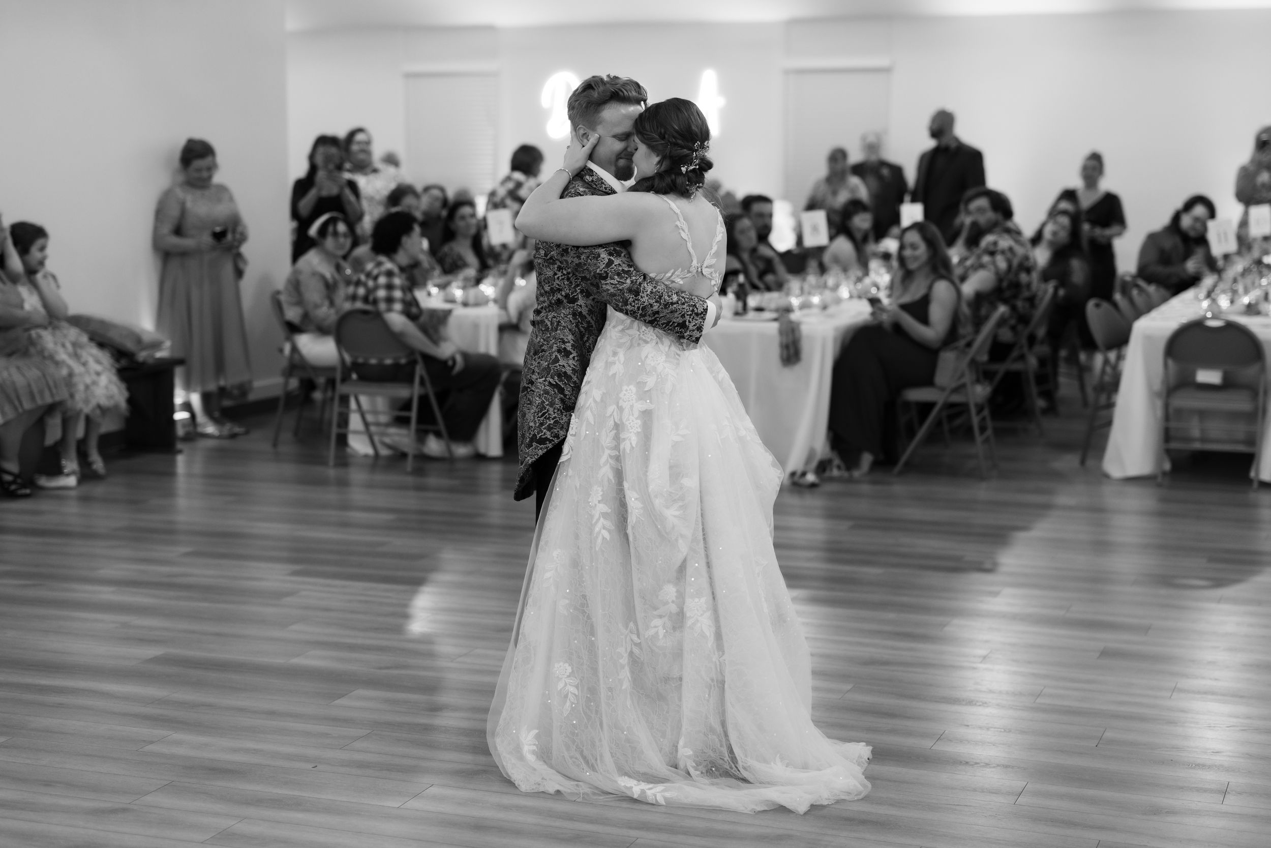 A black and white panoramic view of a wedding reception with guests seated at tables in an elegant ballroom.
