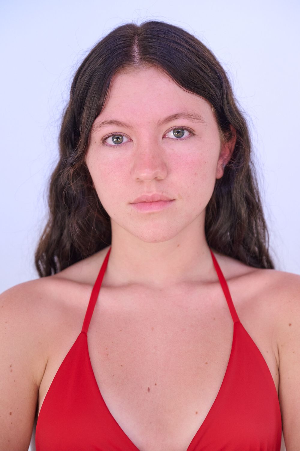 A person with dark hair wearing a red halter top poses in a series of similar headshots against a white background.