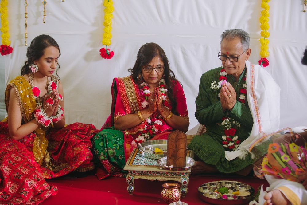 A festive Indian wedding ceremony featuring traditional red and green attire with yellow floral decorations.