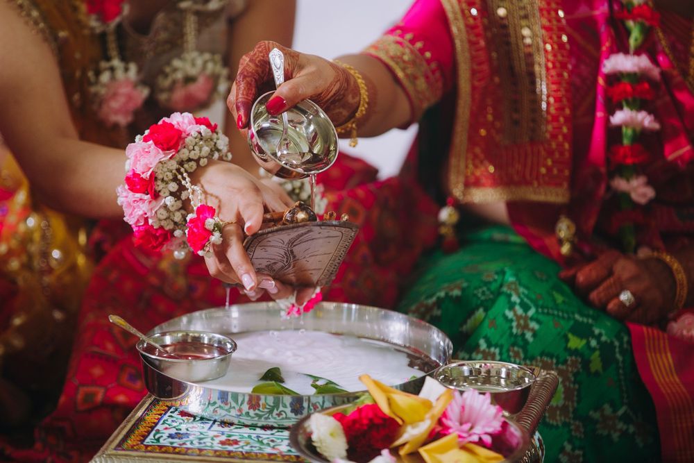 Colorful Indian wedding ceremony with traditional decorations and rituals being performed indoors.