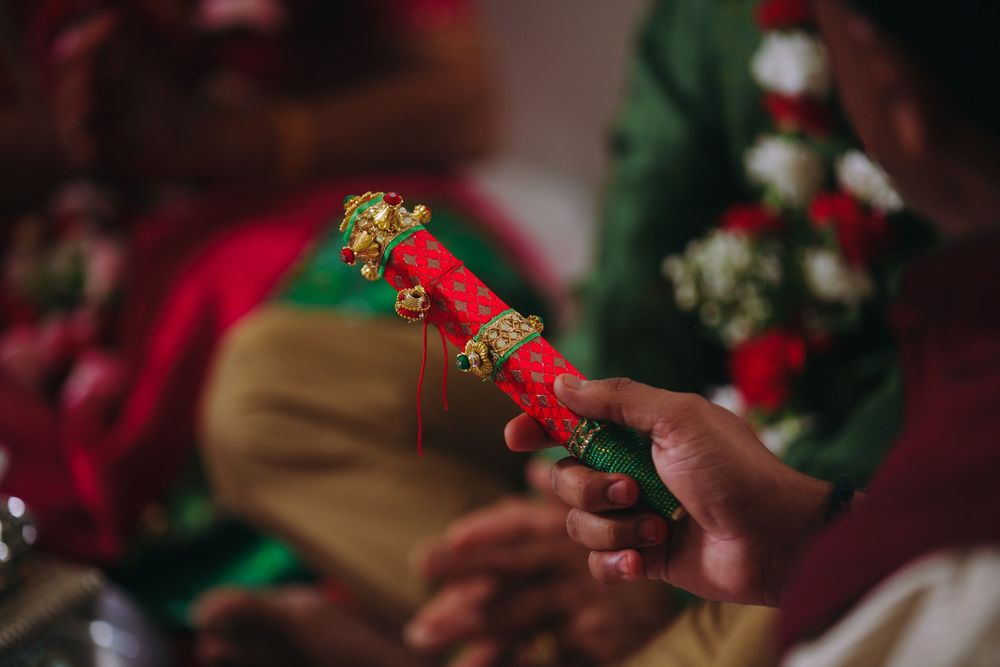 Hands crafting red and green Christmas decorations on a wooden surface with festive holiday supplies.
