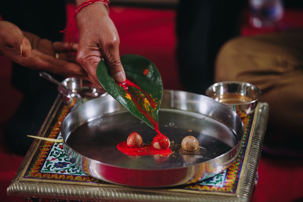 Hands preparing colorful ingredients and dishes on a dark wooden table with vibrant red accents.