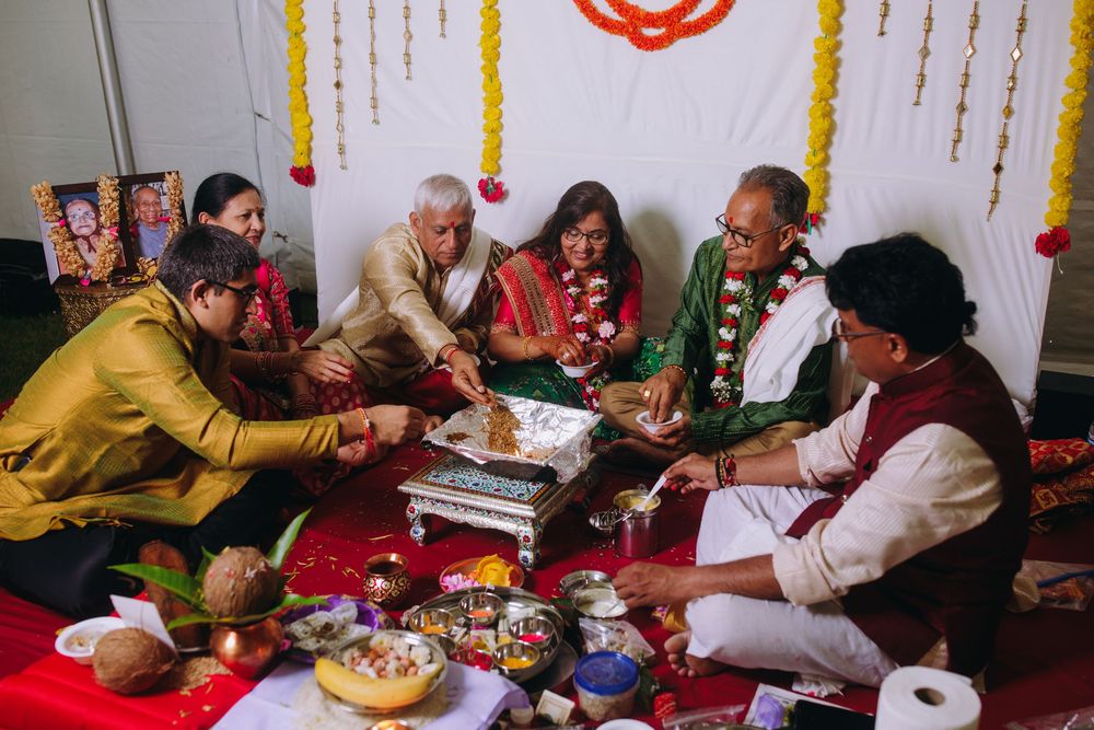 A group of people gather around a table for a traditional Indian ceremony with decorations and offerings.