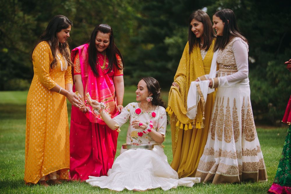 Colorful traditional Indian wedding celebration with guests in vibrant yellow and pink outfits gathered outdoors.