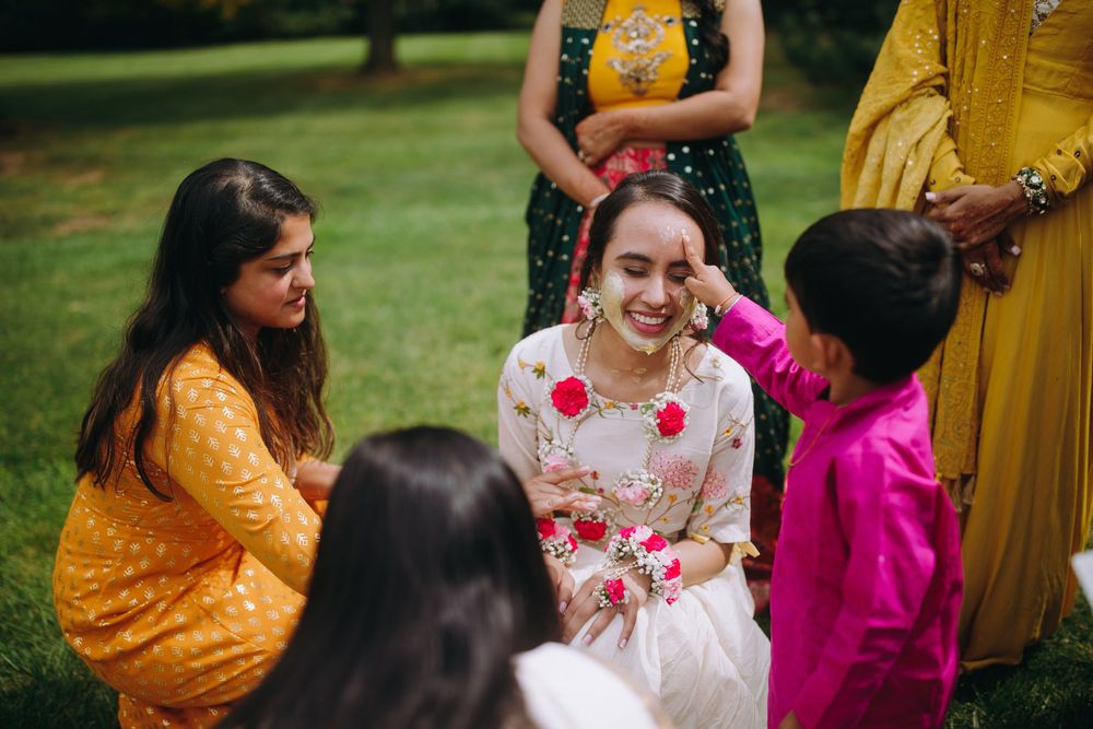 A festive gathering shows people wearing vibrant yellow and pink traditional outfits outdoors.