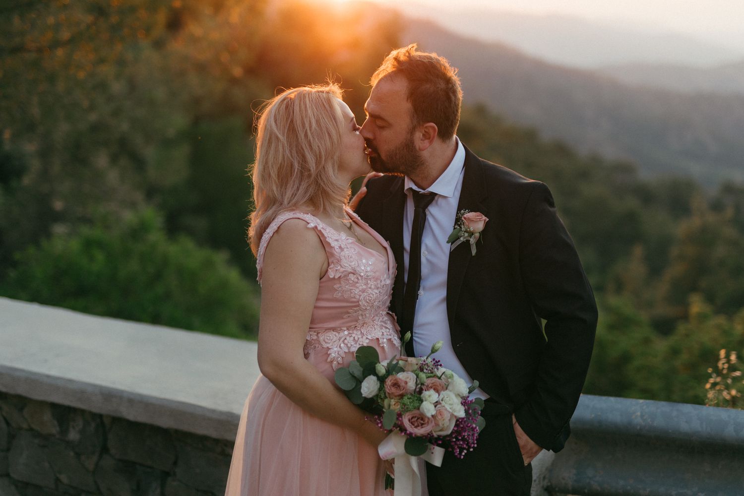 Romantic sunset wedding photos captured at a scenic mountain overlook with pink and orange skies in the background.