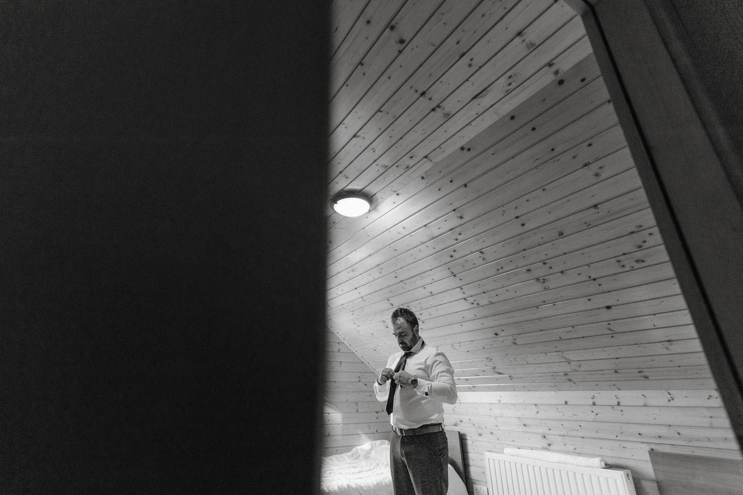 Black and white photo of a wooden ceiling with exposed beams and slanted angles creating dramatic architectural lines.