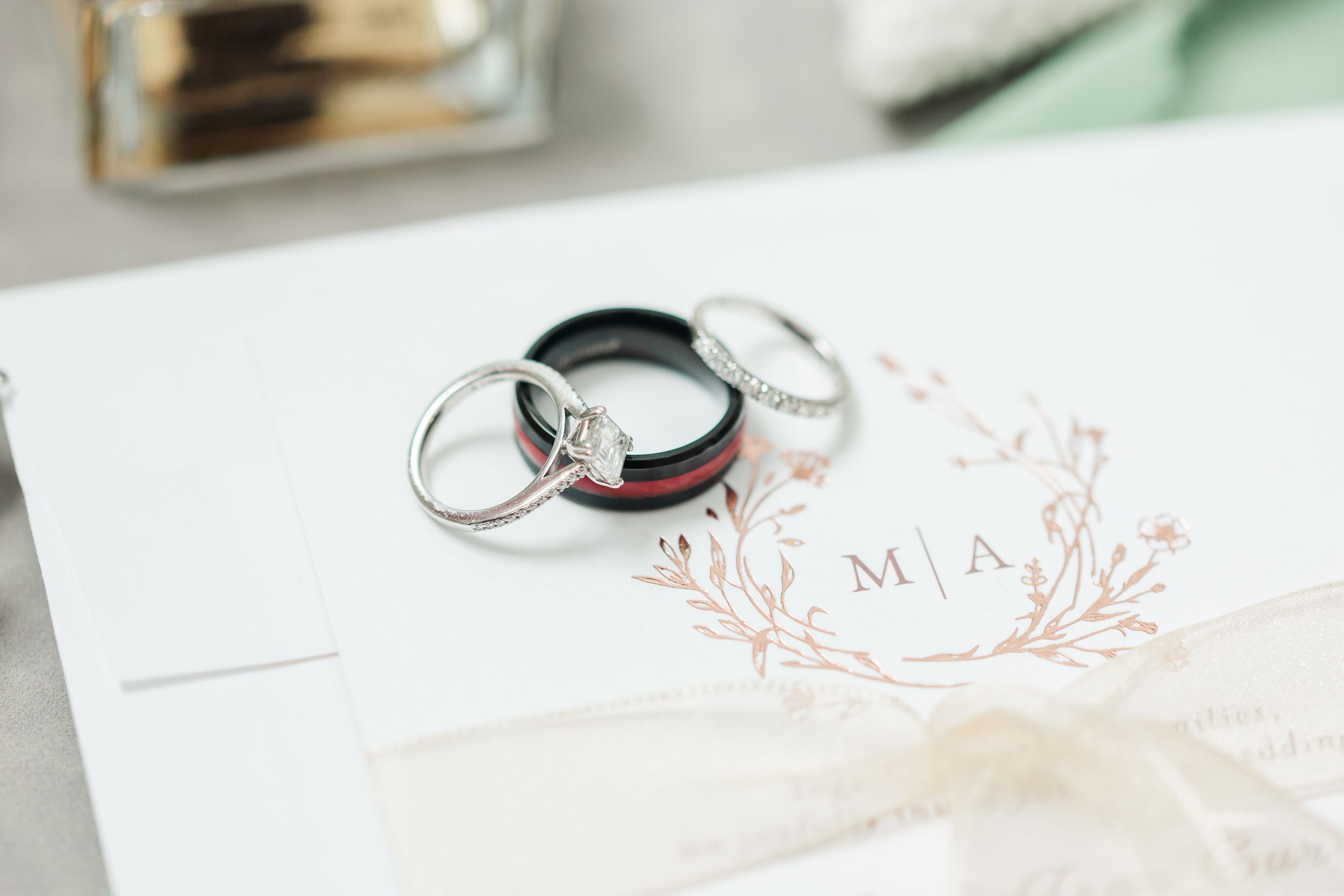 Detail, Close, Color, Neutral, 3. Wedding rings rest on an elegant invitation with rose gold monogram details and delicate floral design.