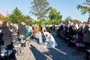 Outdoor wedding ceremony setup with rows of white chairs on a sunny patio.