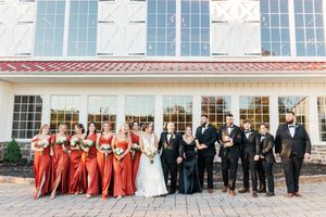 Wedding party lined up outside a classic venue with large windows and stone facade.