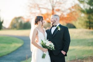 Romantic autumn wedding portraits with white bouquet and formal attire against fall foliage.