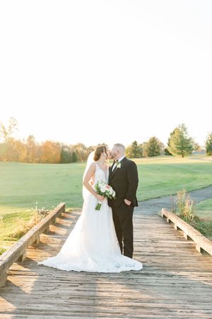 Wedding couple walks along wooden boardwalk during golden hour sunset.