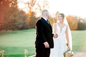 Couple walking together in golden sunset light during outdoor fall wedding portraits.