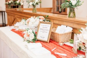 Wedding reception decor featuring elegant floral centerpieces and wooden accents with red table runners.