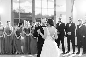 Black and white wedding ceremony with bridal party in formal attire in an elegant venue.
