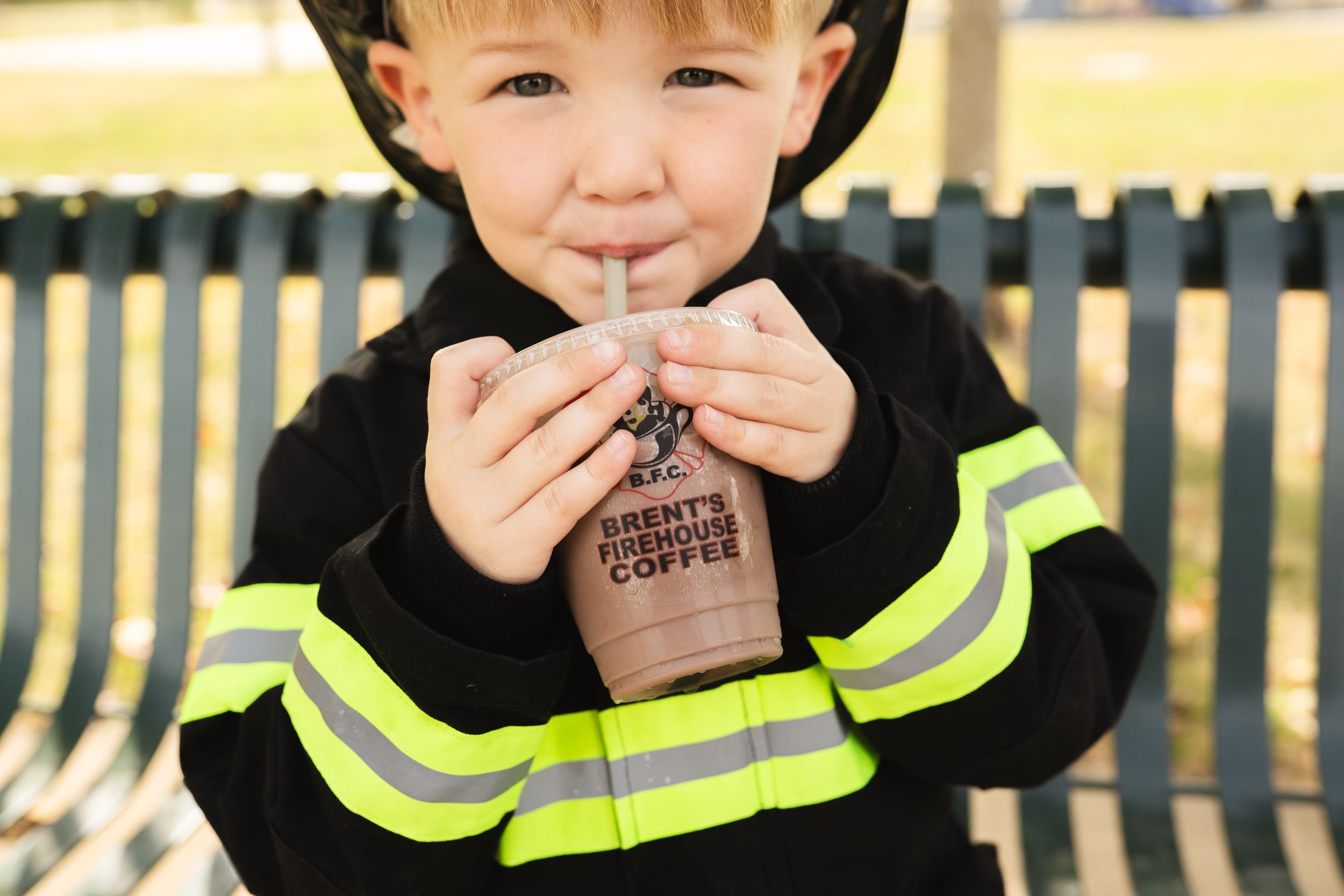 Figure in black firefighter costume with yellow reflective stripes enjoying a beverage.