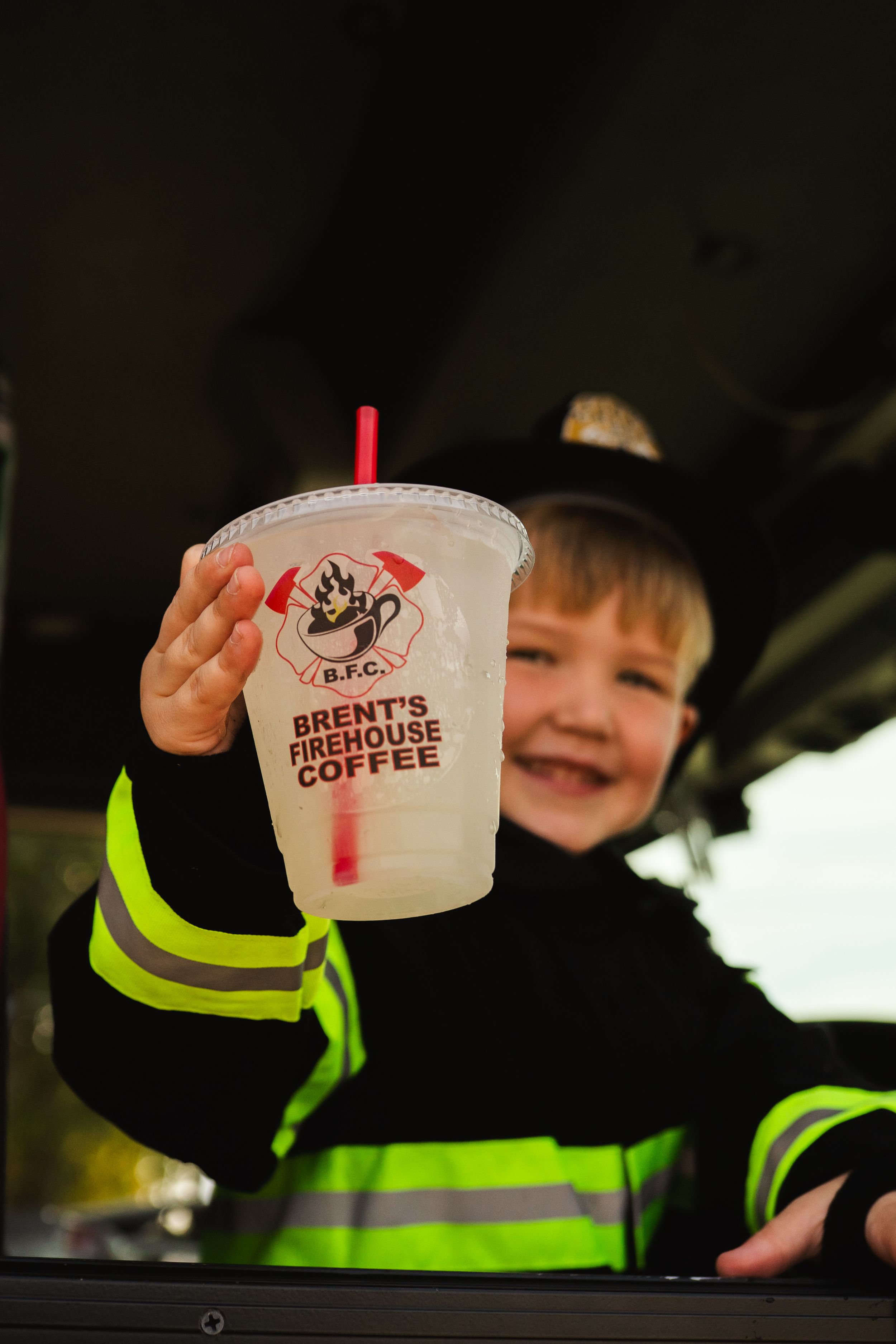 Figure in firefighter costume holding Brent's coffee cup in dark setting.