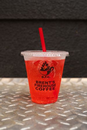 Red branded disposable cups from Brent's Firehouse Coffee on a metallic surface.