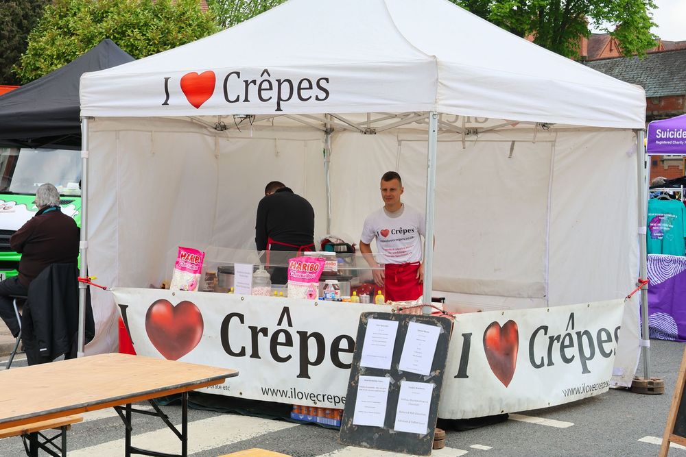 Outdoor crepe stand with white canopy displaying I Love Crepes branding at a street food market event.