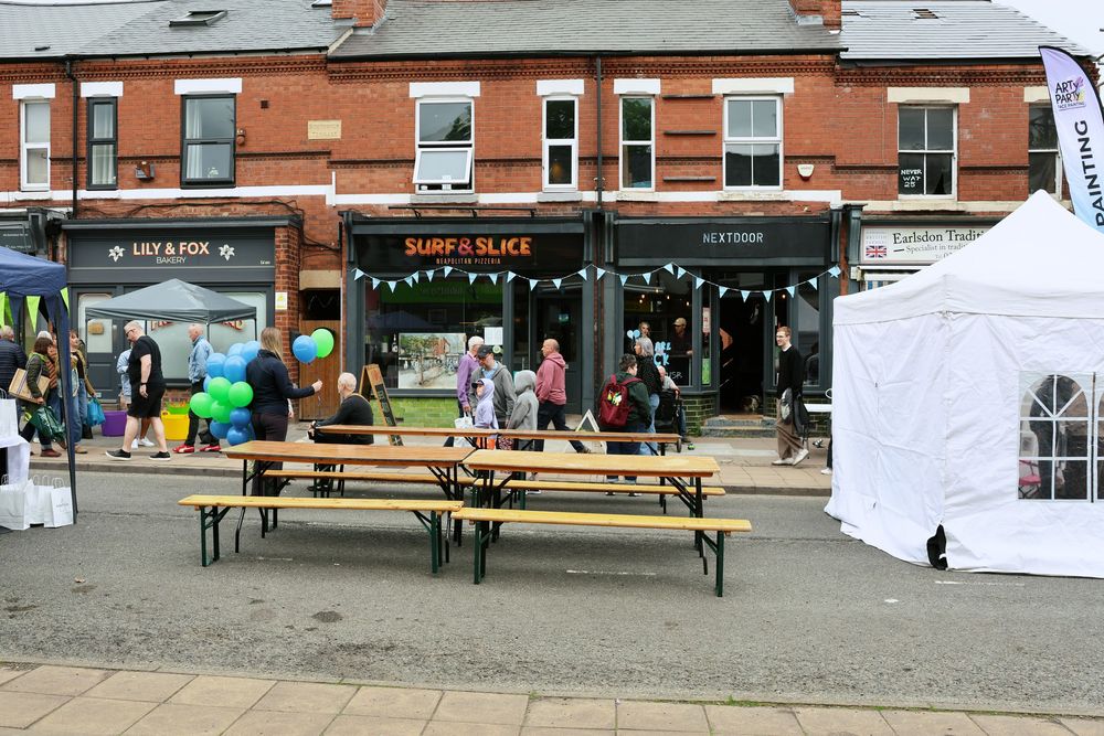 Surf and Slice shop frontage with outdoor picnic benches and white marquee at Earlsdon street festival.