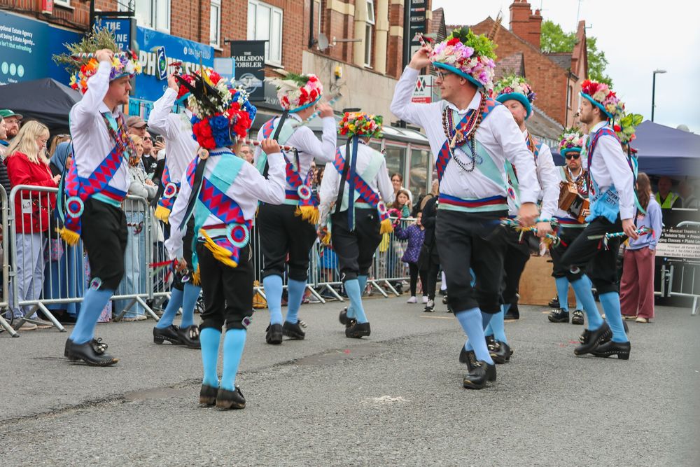 Traditional Morris dancers in colorful costumes performing at an outdoor street festival in Earlsdon.