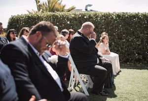 A wedding party laughs together while walking through a garden setting during an outdoor celebration.