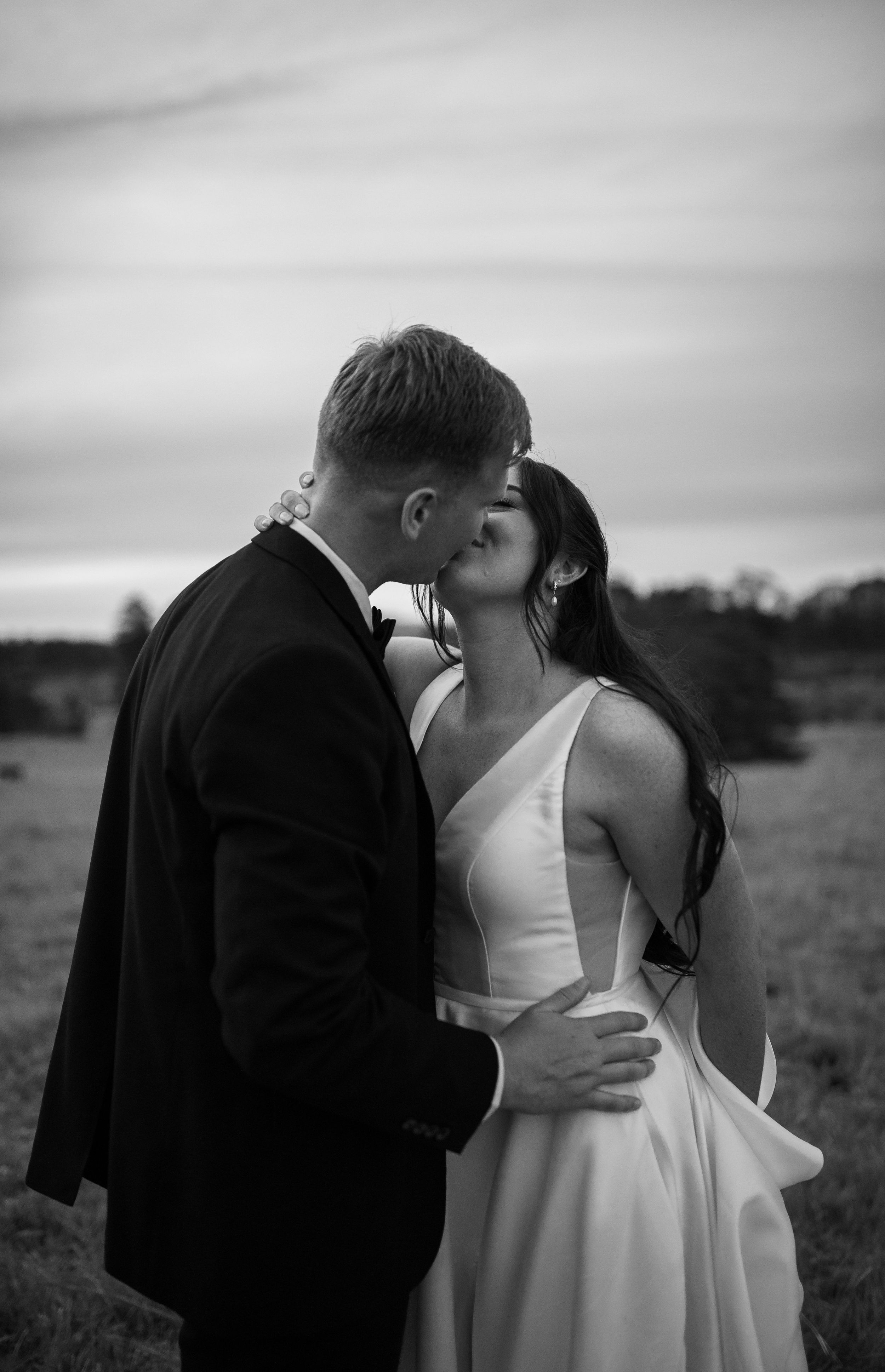 Black and white romantic moment between newlyweds in an open field.