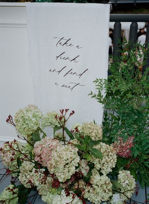 Elegant wedding signage with calligraphy text surrounded by white hydrangea flowers.