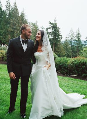 Couple in wedding attire shares intimate dance moves on an outdoor lawn with mountain views.