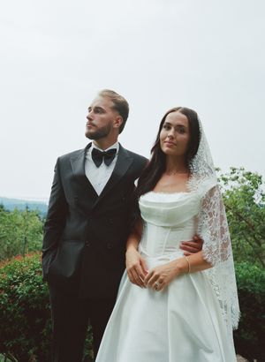 A romantic wedding photoshoot outdoors with a couple in formal attire against a scenic natural backdrop.